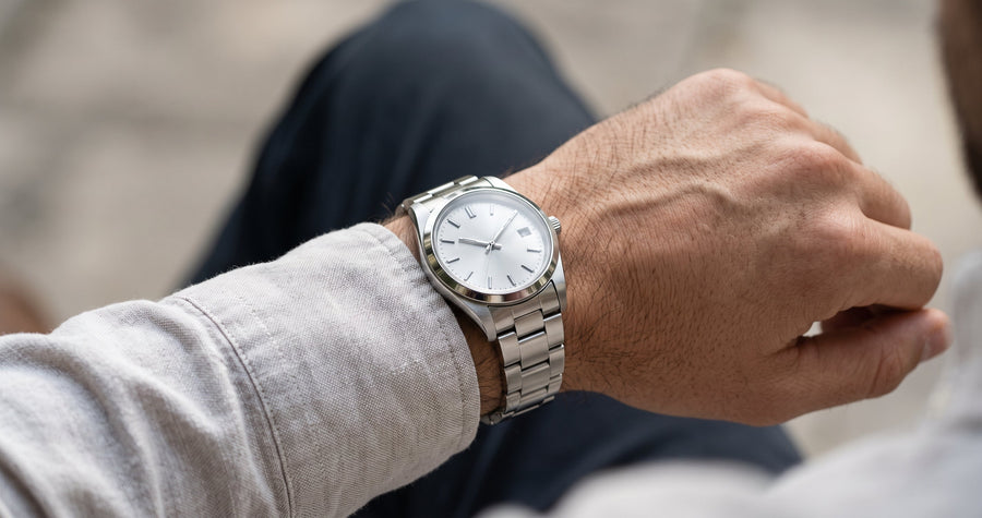 Steel watch bracelet on the wrist with a linen shirt cuff